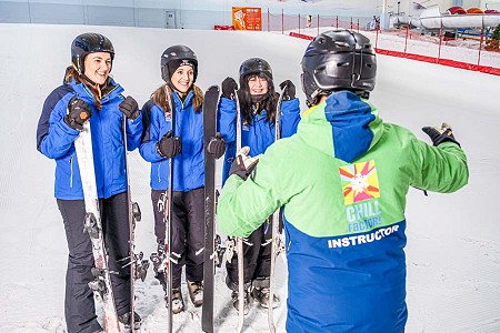 A ski instructor speaking to 3 women, all in blue jackets. They are holding their skis and smiling.